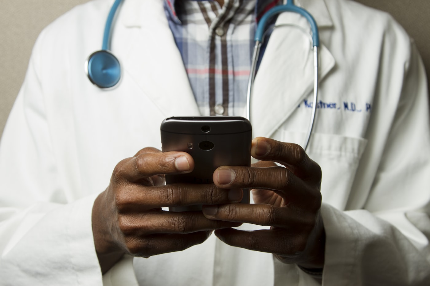 A doctor in a white coat using a phone